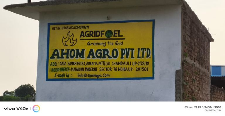 Painted signboard at the Chandauli site reading AGRIDFUEL, Ahom Agro Pvt Ltd, with GSTIN and both addresses.